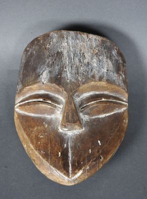 gros plan d'un masque en bois sur une surface grise