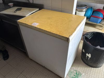 une photo d'une cuisine avec une poubelle et un réfrigérateur