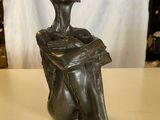 sculpture en bronze représentant une femme assise sur une table