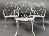 trois chaises blanches en fer forgé et une table sur fond gris