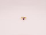 gros plan d'une bague en or avec une pierre violette