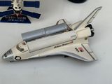 une maquette de navette spatiale posée sur une table, à côté d'une navette spatiale miniature
