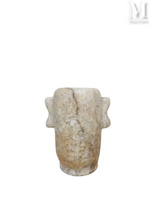 un vase en pierre posé sur une surface blanche