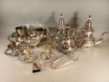 un service à thé en argent posé sur une table, à côté d'autres objets en argent