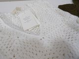 a white crocheted sweater with a tag on it