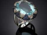 a close up of a ring with a large blue stone surrounded by blue sapphires