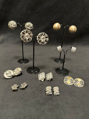 a group of silver and gold earrings and brooches on stands