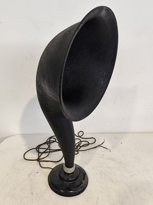 un vieux gramophone noir posé sur une surface blanche, avec un cordon