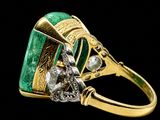 a close up of a ring with a green stone surrounded by diamonds