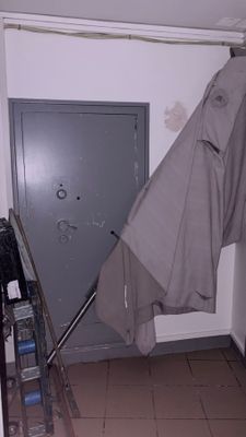 a coat hanging on a hook in the corner of a room