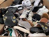 plusieurs paires de chaussures dans une boîte en carton posée sur le sol