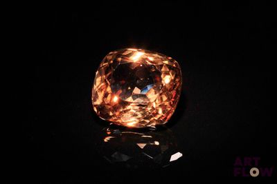 an orange diamond on a black surface with a black background