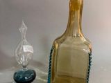 a glass bottle and a glass candle holder on a table