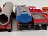many toy trucks that are lined up together on a white surface