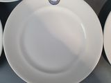 four white plates with a gold and blue emblem are on a table