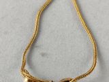 a gold plated necklace with two small beads on a gold chain