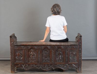 Il y a quelqu'un assis sur un banc, vêtu d'une chemise blanche.