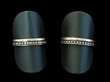 une paire de bagues en argent ornées de diamants noirs, sur fond noir