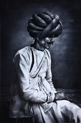 photographie en noir et blanc d'une femme portant un turban, assise sur un lit