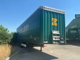 a green semi trailer parked in a parking lot
