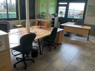 a room with a desk, chairs, and a computer on it