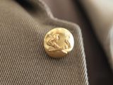 a gold button on the lapel of a man ' s jacket