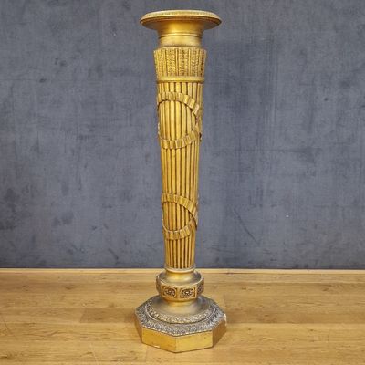 un vase en or posé sur une table en bois, avec un mur gris en arrière-plan