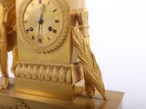 a gold clock with a statue of a woman holding an umbrella