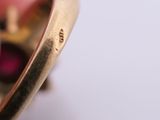 a close up of a gold ring with a red stone in it