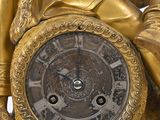 a gold statue of a man sitting on a clock