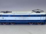 un train bleu et blanc sur les rails, sur un fond gris