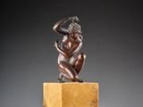 a bronze statue of a woman sitting on top of a marble block