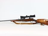 the rifle is sitting on a stand with a scope on it ' s side