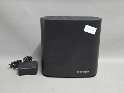 un gros plan d'une enceinte noire avec un chargeur posée sur une surface blanche