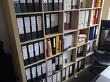 a room with a desk, a chair, a bookcase and a computer