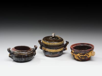 trois petits pots munis d'anses sont posés sur une table