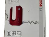 packaging of a red electric hand blender sitting on top of a white box