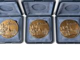 three gold medals are in a blue case on a white surface