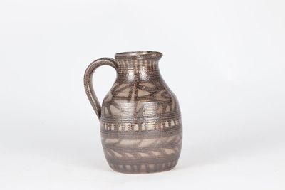 une image représentant un vase marron posé sur une surface blanche