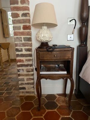 une petite table sur laquelle est posée une lampe, à côté d'un lit