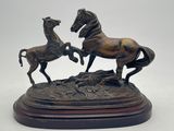 statue en bronze représentant deux chevaux, posée sur un socle en bois, sur fond blanc