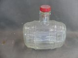 a clear glass bottle with a red cap sitting on a table