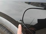 a person ' s hand pointing at the side of a black car