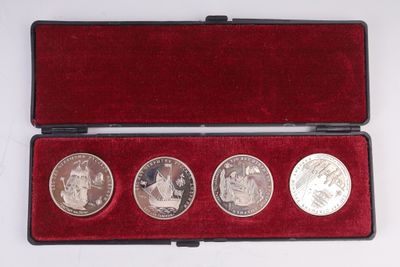 trois pièces d'argent dans un étui en velours rouge posé sur une surface blanche