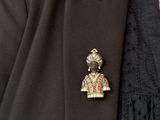 a close up of a person wearing a suit and tie with a broochet