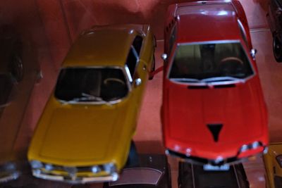 Plusieurs petites voitures sont alignées sur une étagère dans une vitrine.