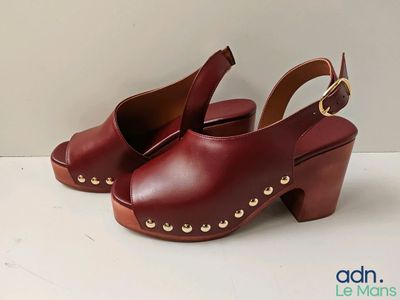 Les chaussures de cette femme sont en cuir rouge et ornées de clous dorés.