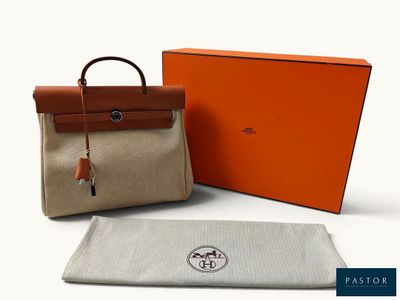 un gros plan sur un sac et une serviette posés sur une surface blanche