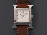 a close up of a watch on a black surface with a brown strap