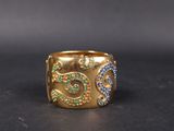 a close up of a gold ring with blue and green stones